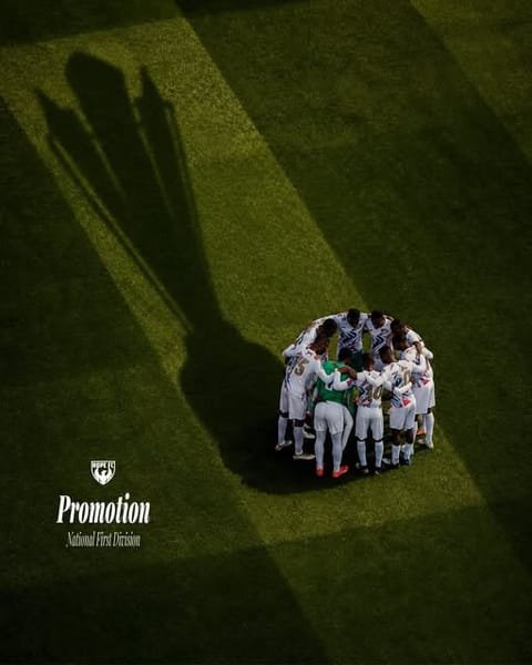 Hope FC players in a huddle on the pitch after winning promotion